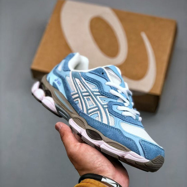 Blue and white sneaker held in a hand with a brown box in the background