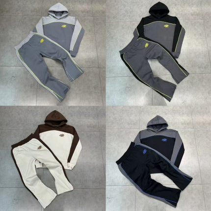 Four different color options of a hoodie and pants set on a tiled floor.