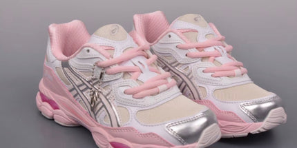 White and pink sneakers with metallic silver accents and pink laces on a gray background.
