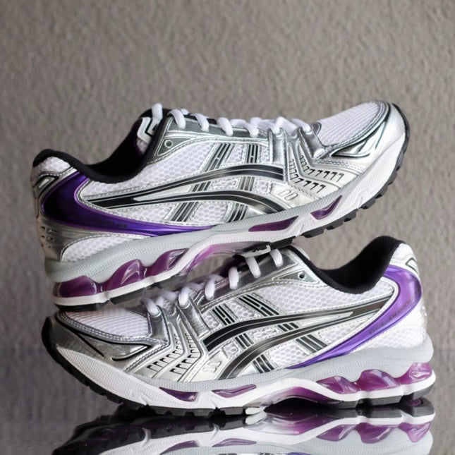 White sneakers with silver accents and purple details, featuring a reflective surface below.