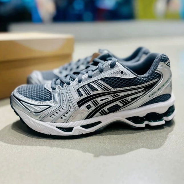 Gray and black athletic shoes with intricate patterns and mesh texture on a light surface.