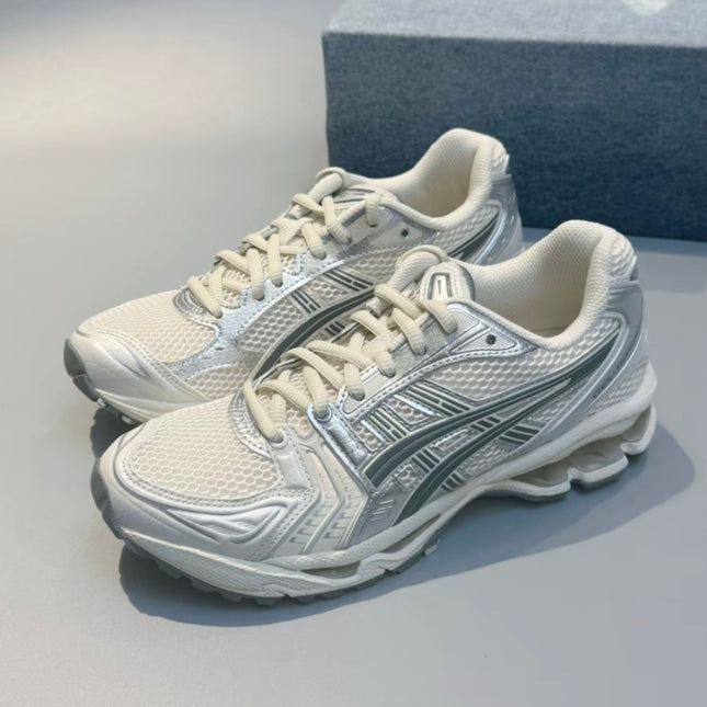 White and silver athletic shoes with mesh texture and intricate detailing on a gray surface.