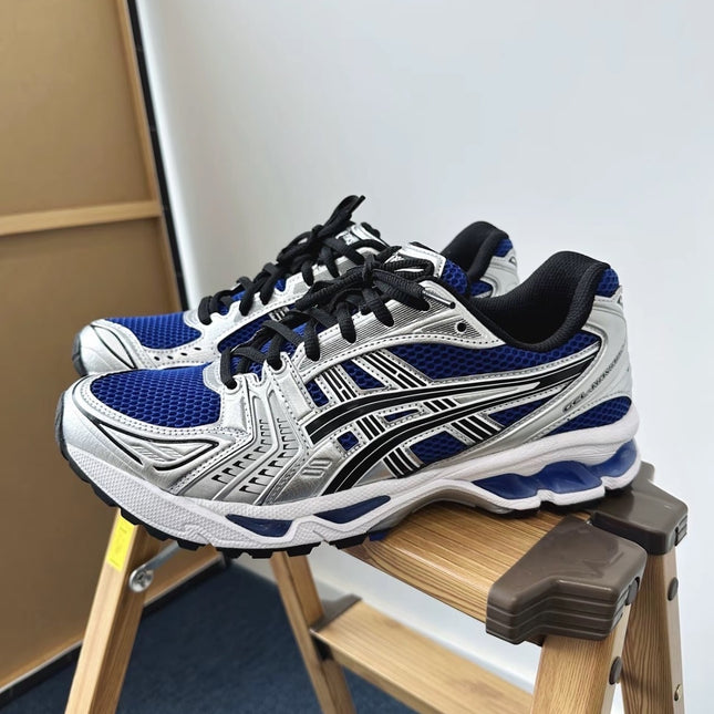 Blue and silver athletic shoes with black laces on a wooden stool against a white background.