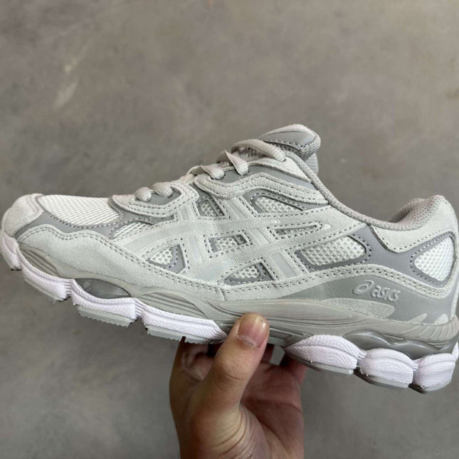 White and gray sneaker held by a hand on a gray background