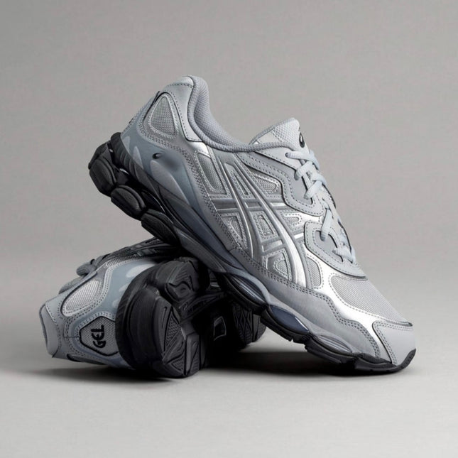 Silver athletic shoes with black soles, featuring intricate pattern details, on a gray background.