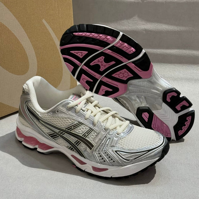 White and silver sneaker with black and pink accents, showing tread and mesh texture. Box in background.