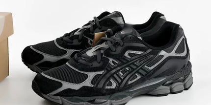 Black and gray athletic shoes with mesh texture and intricate sole, next to a cardboard box.