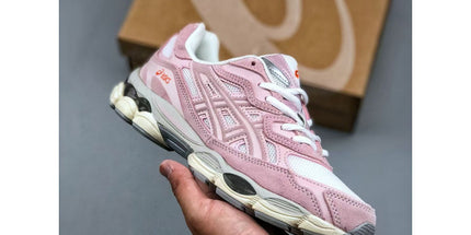 Pink sneaker held in a hand with a brown box in the background