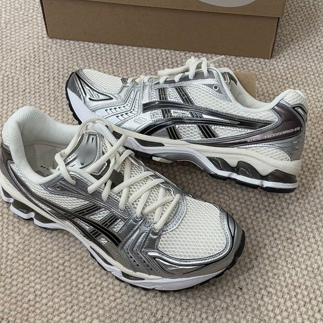 White and silver athletic shoes with black accents on a beige carpet.