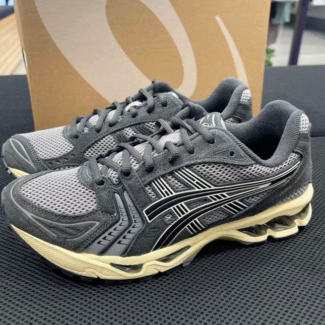 Gray athletic shoes with mesh upper, black stripes, and beige soles on a black surface.