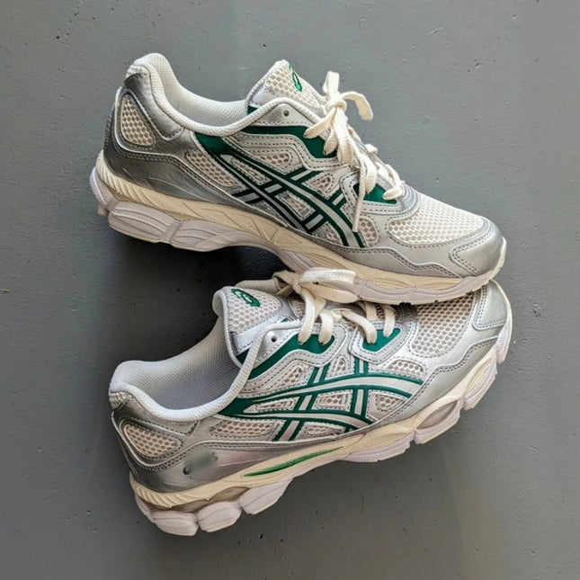 White and silver athletic shoes with green accents and white laces on a grey background.