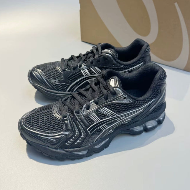 Black athletic shoes with silver accents, mesh texture, and lace-up design on a light surface.