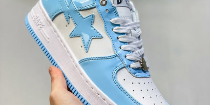 Blue and white sneaker with star design held by a hand against a neutral background