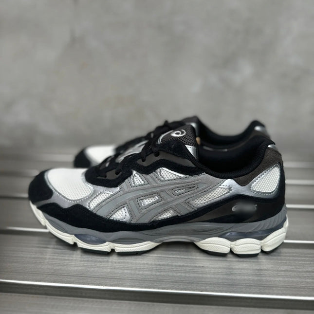 Gray sneakers with black and white accents on a metal surface, featuring a mesh and leather design.