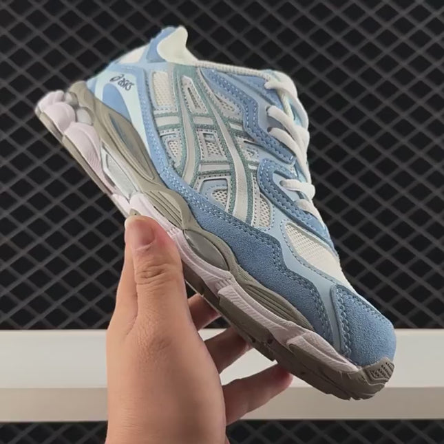 Blue and white sneaker with mesh and suede, held by hand, against a dark grid background.