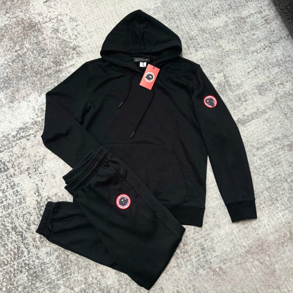 Black hoodie and pants set with red patches on a gray surface